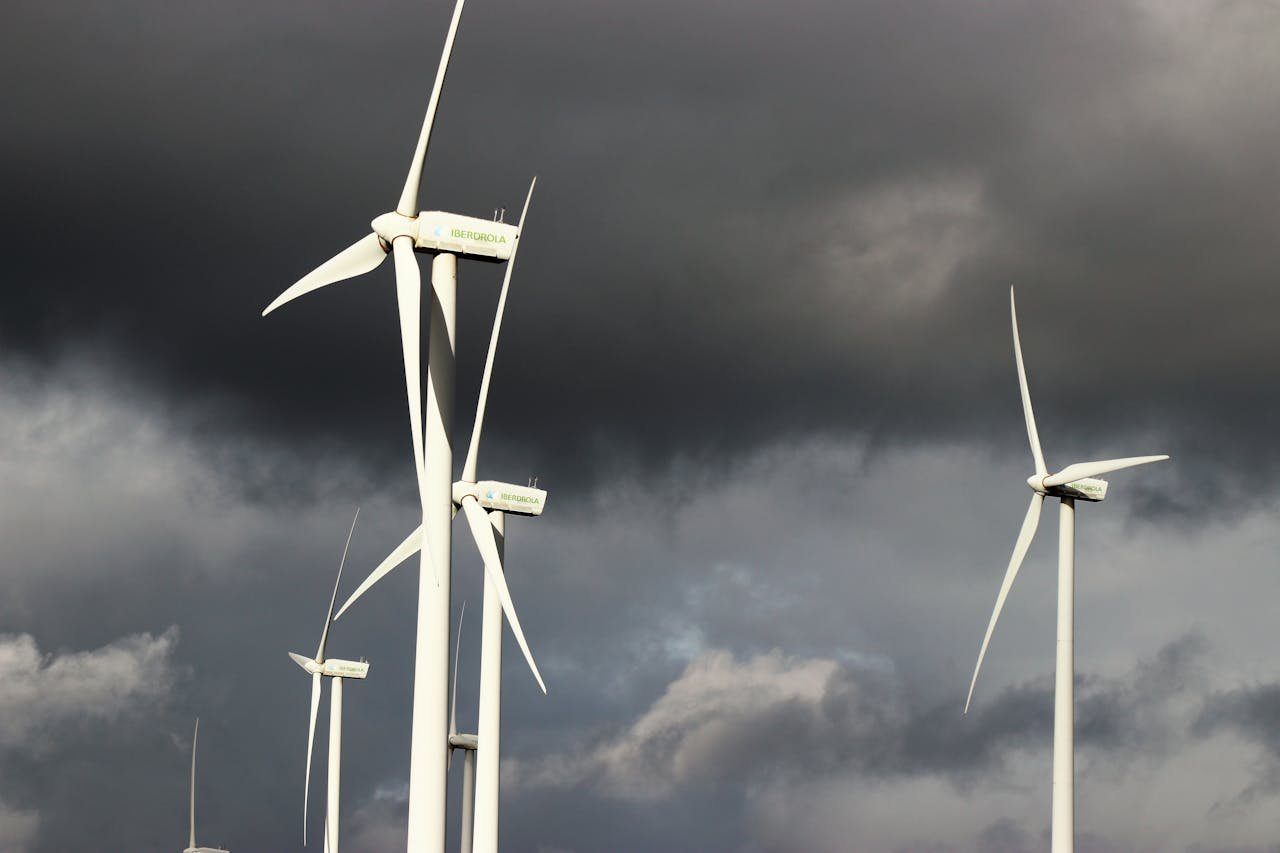 Wind turbines with dark storm clouds in the background, highlighting renewable energy amid powerful weather conditions.